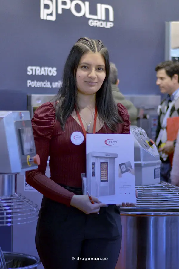 Mujer joven con camisa vinotinto y pantalón negro, modelando con catálogo de hornos para panadería, gastronomía y heladería de las marcas Polin, Angelo Po y Sottoriva. Fotografía por dRaGoNian. 
